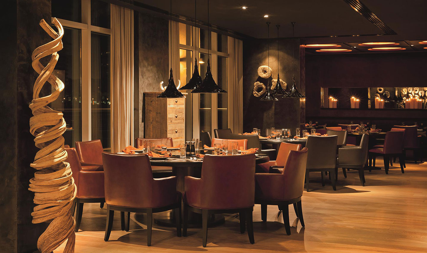 The chocolate-coloured interior of Toro Toro Dubai with round dining tables and soft lighting and an intimate atmosphere